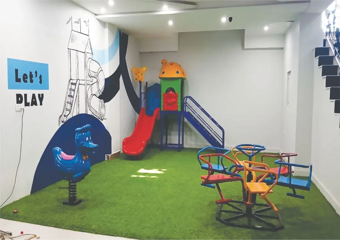 Indoor play area at London School Lahore with soft flooring, slides, and ride-on toys for early years children